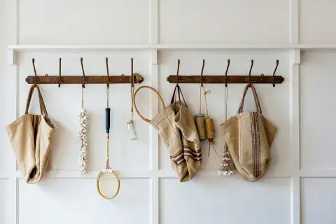 Hooks: brown and white sling bags hanged on white wooden wall