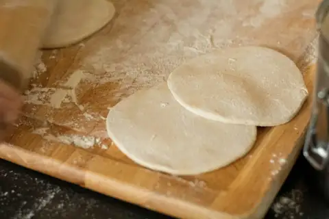 Chakla & belan: white dough on brown wooden chopping board