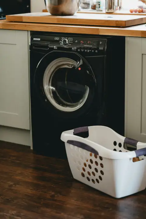 Baskets: white plastic laundry basket beside black front load washing machine