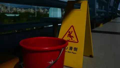Mops: A red bucket sitting next to a yellow caution sign