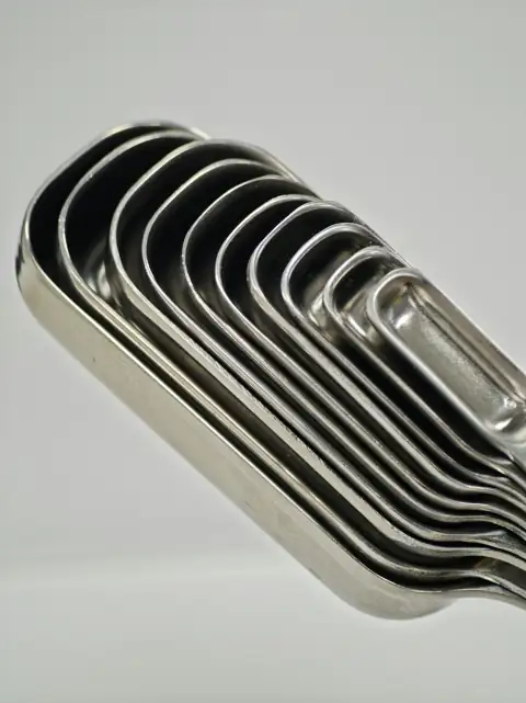 Steel utensils: Stacked stainless steel measuring spoons on white